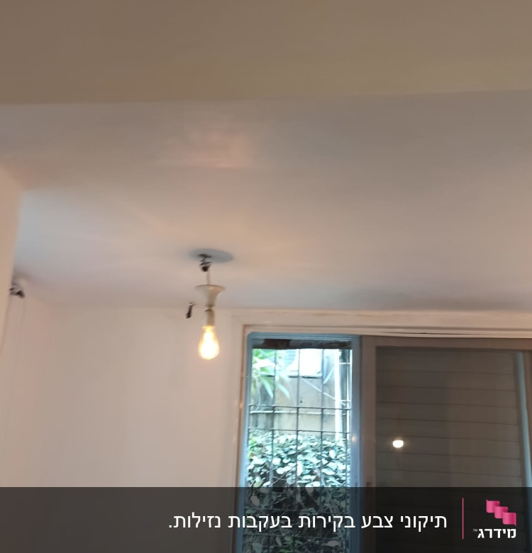 נורה חשופה תלויה מהתקרה בחדר משופץ
